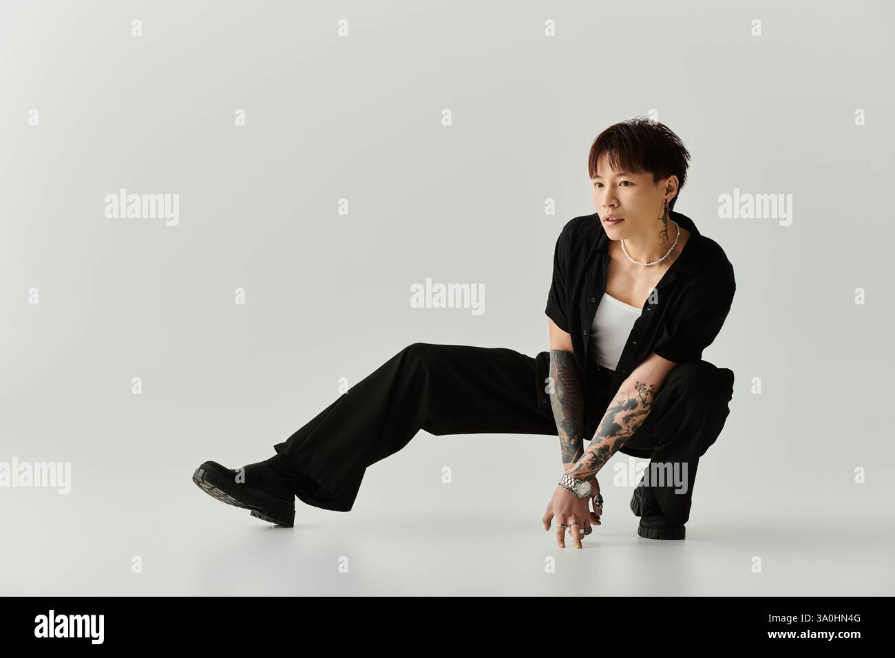 A young handsome Asian man strikes a dynamic pose in a clean, minimalist studio space. Stock Photo