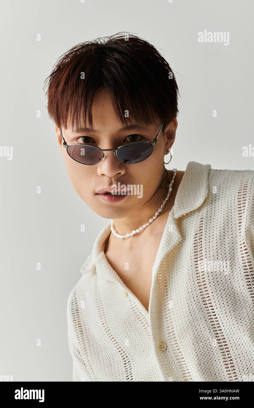 A young, stylish Asian man poses confidently with unique accessories. Stock Photo