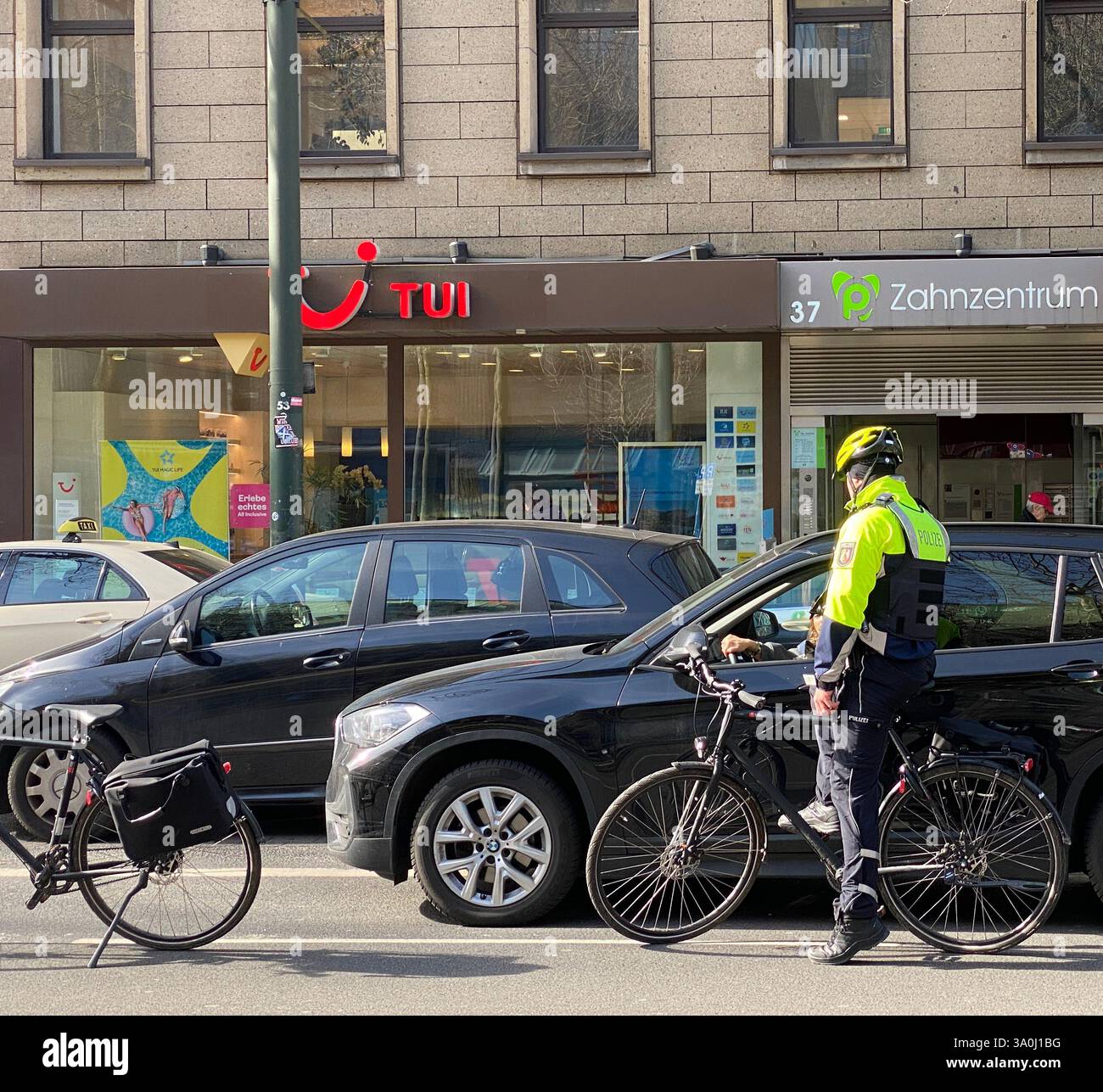 Zwei Fahrradpolizisten kontrollieren ein Fahrzeug, das auf dem Fahrradweg angehalten hat. Die Polizisten sind selbst mit Fahrrädern in der Innenstadt. - Smartphone Captured Stock Image