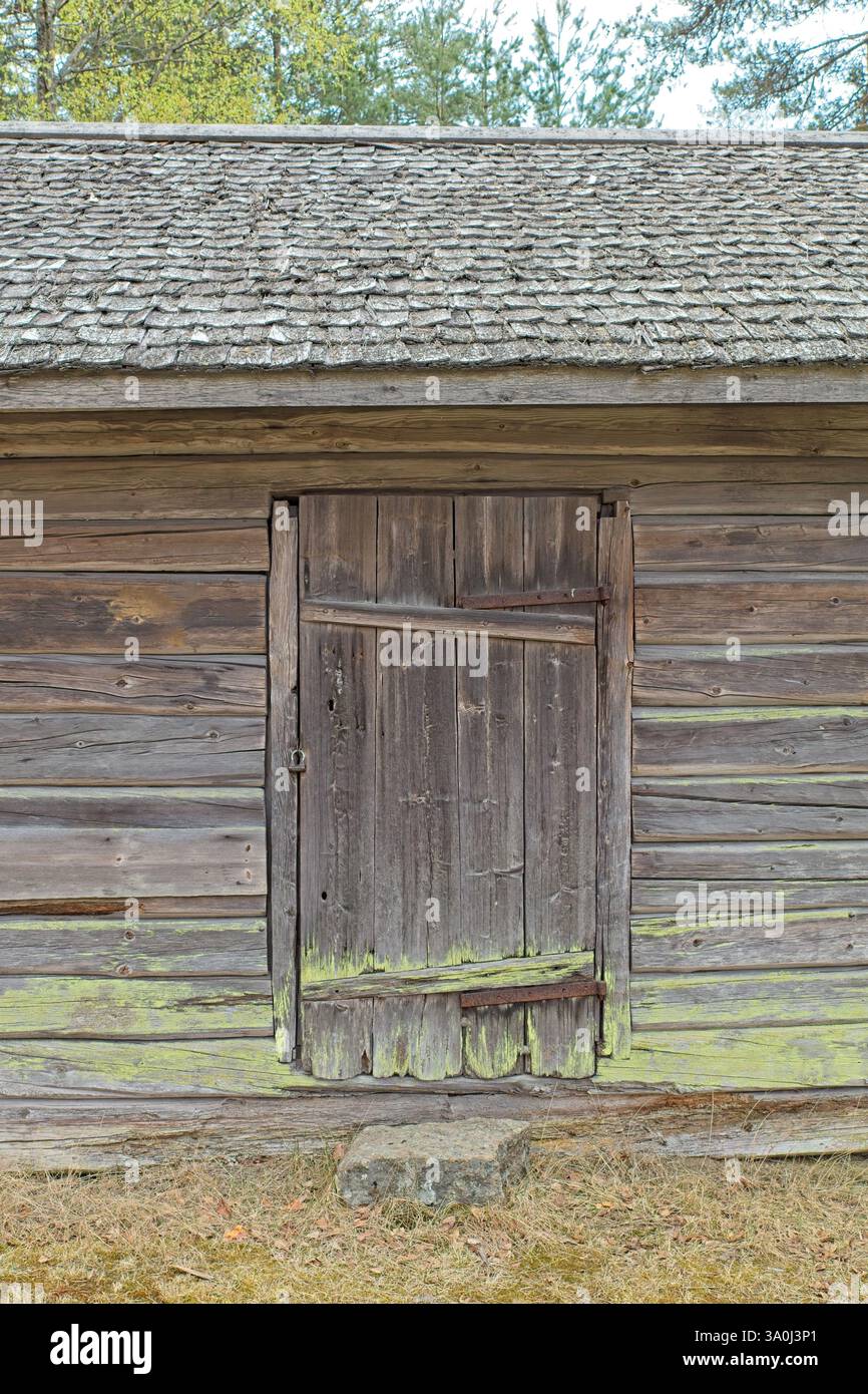 Weathered closed wooden door on an old log building, Finland. Stock Photo