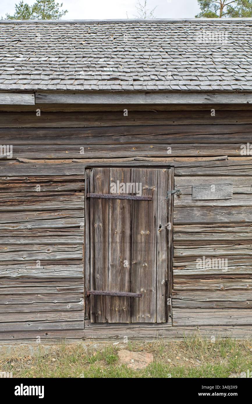 Weathered closed wooden door on an old log building, Finland. Stock Photo