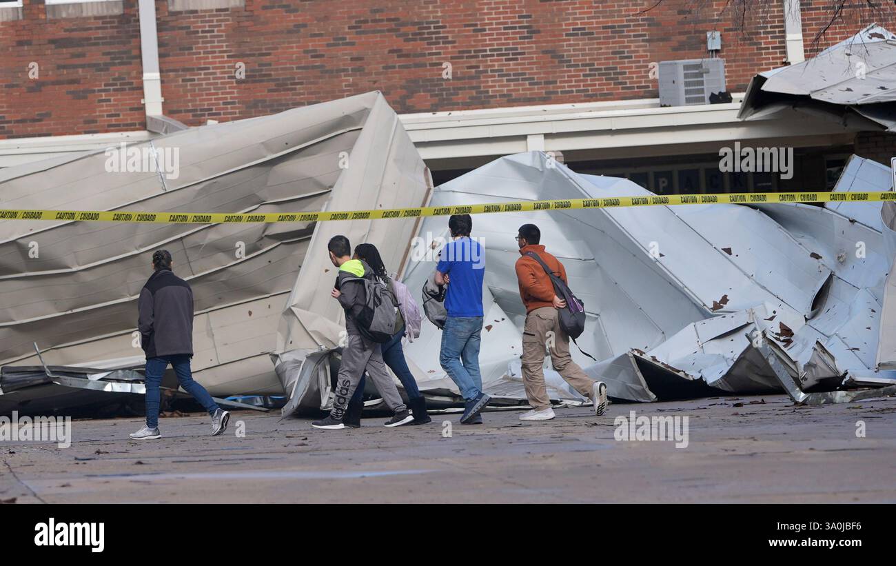 Students arriving for classes walk past damage from the roof that was