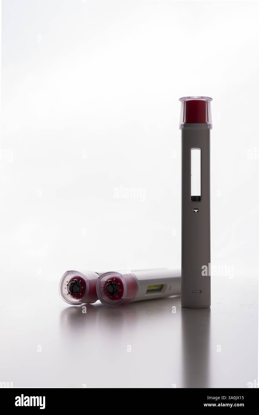 A group of pen injectors with a red tip for biological treatments such ...