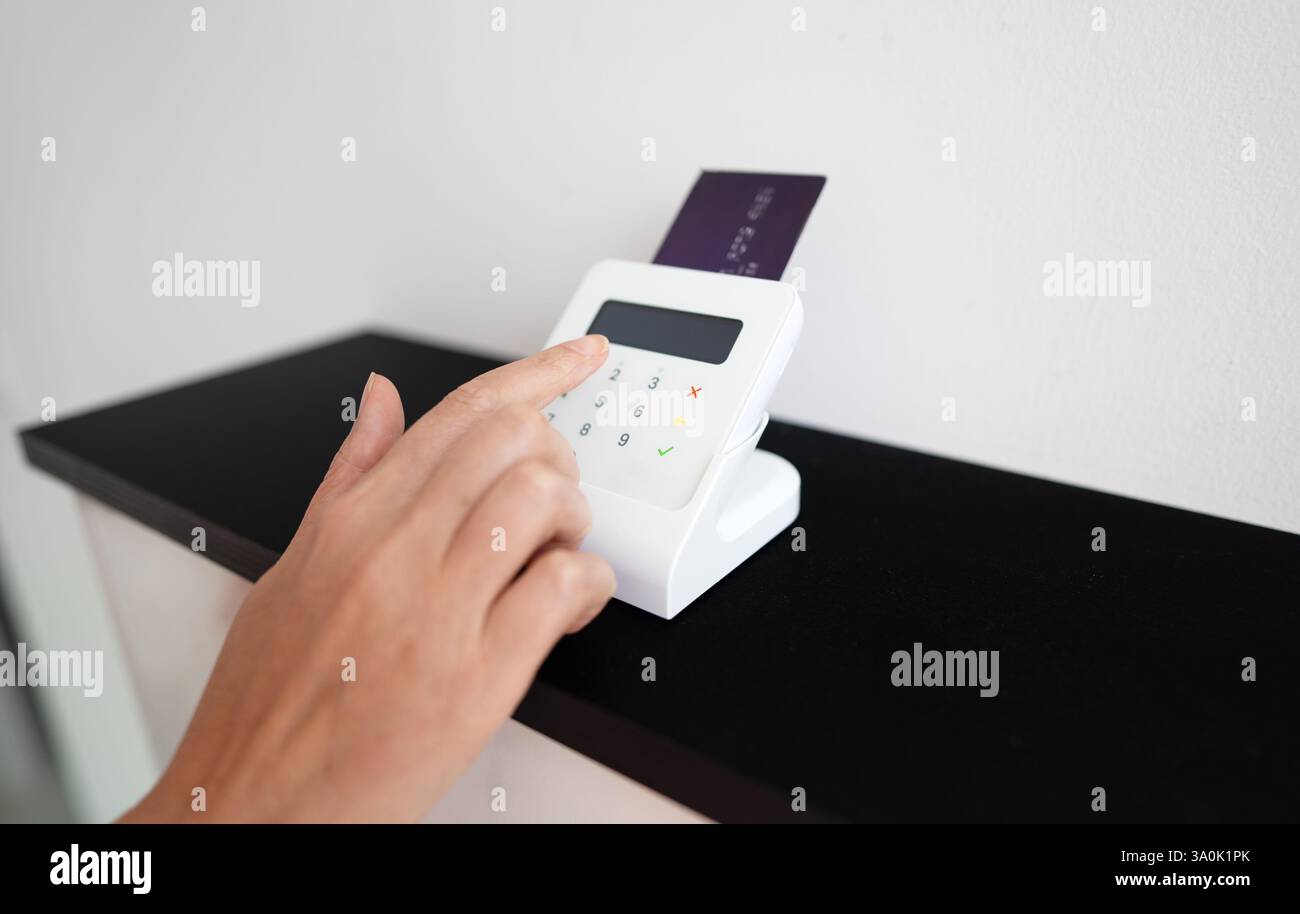 Woman's hand entering a PIN code on a wireless payment terminal Stock Photo