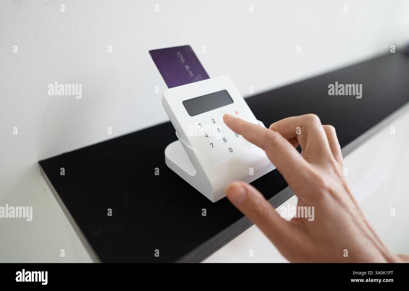 Woman's hand entering a PIN code on a wireless payment terminal Stock Photo