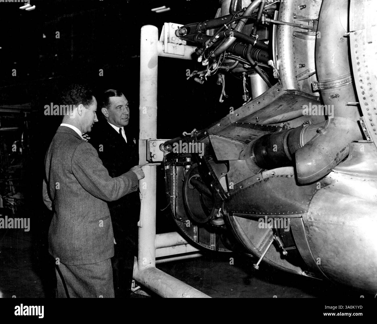 British Commonwealth Pacific Airlines Executive Views New Stratocruisers -- Mr. A. A. Barlow (right) manager of British Commonwealth Pacific Airlines, inspects details of a Boeing Stratocruiser 'Power Package' with E.E. Miller, Boeing Assistant Sales Manager. During a recent inspection tour of the Boeing facilities in Seattle, Mr. Barlow and his party from BCPA were the production progress on flects of the new luxury airliners, now under construction for six major world airlines. All four 'Power packages' incorporating engine, turbo super charger, intercooler, oil system, and accessories are i Stock Photo