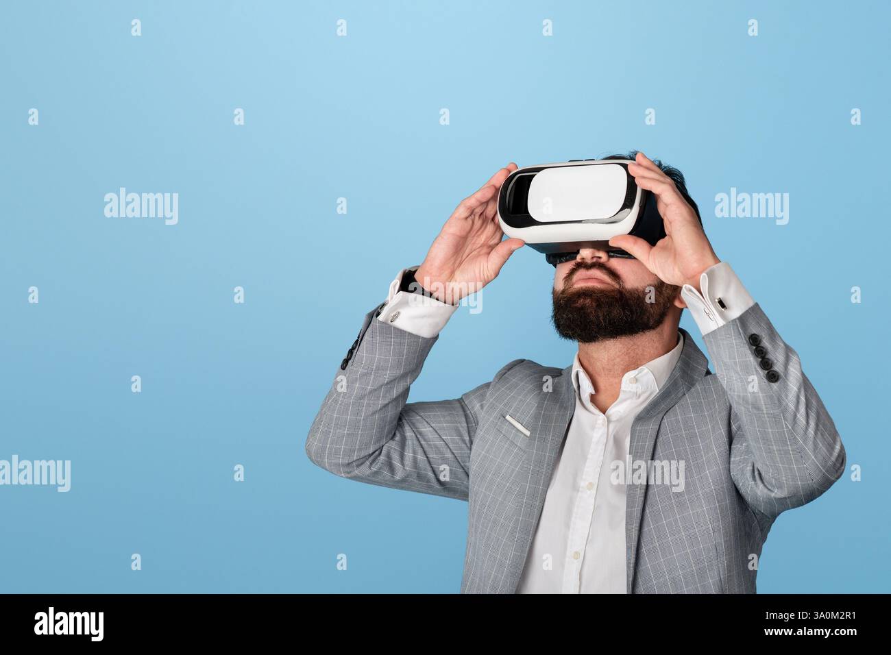 Businessman in virtual reality headset exploring cyberspace on blue background Stock Photo