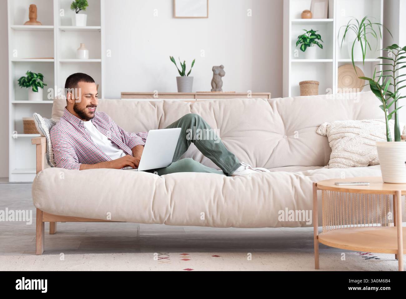 Freelancer lying on sofa and using laptop at home Stock Photo