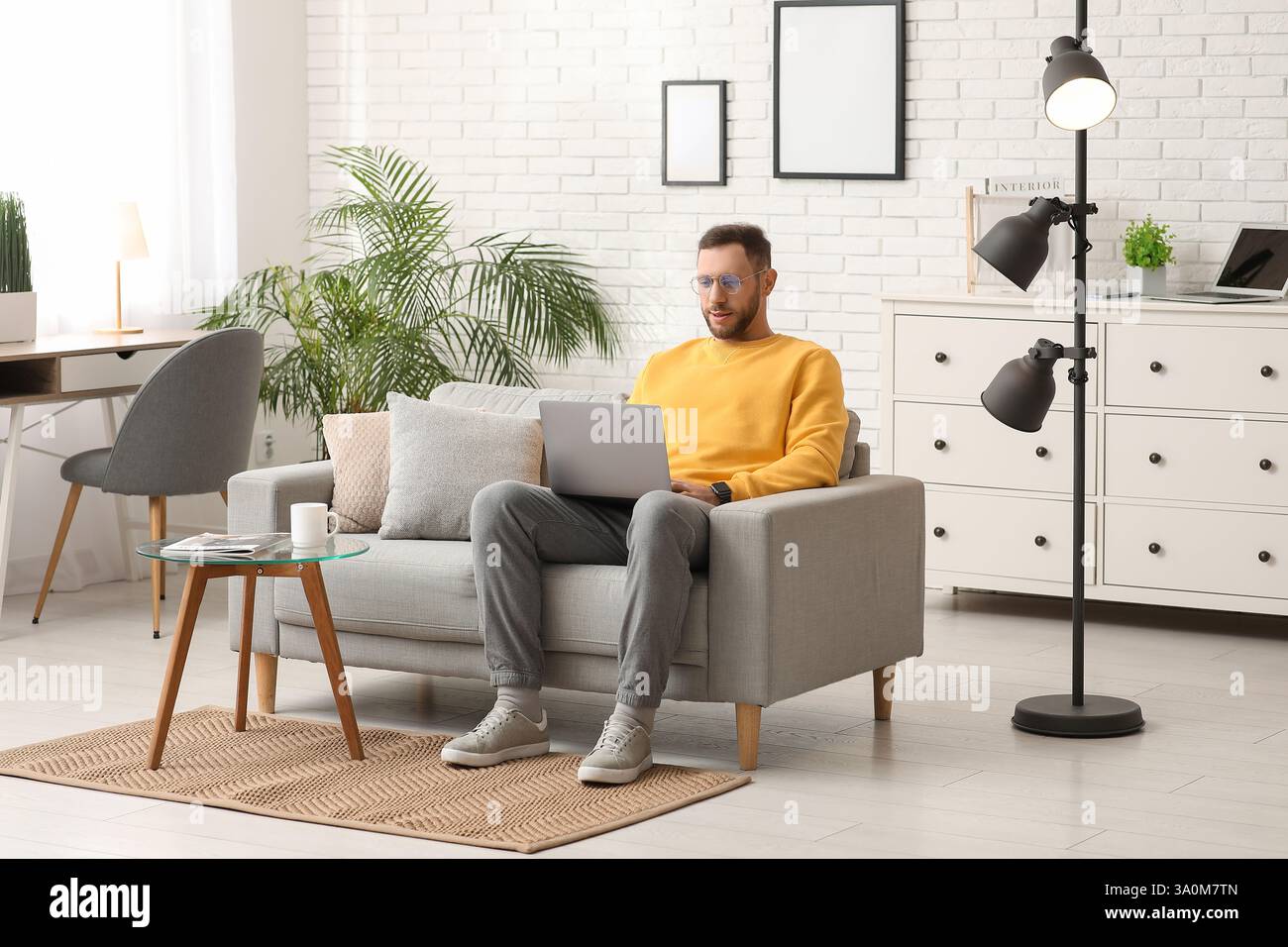 Young man using laptop on sofa at home Stock Photo