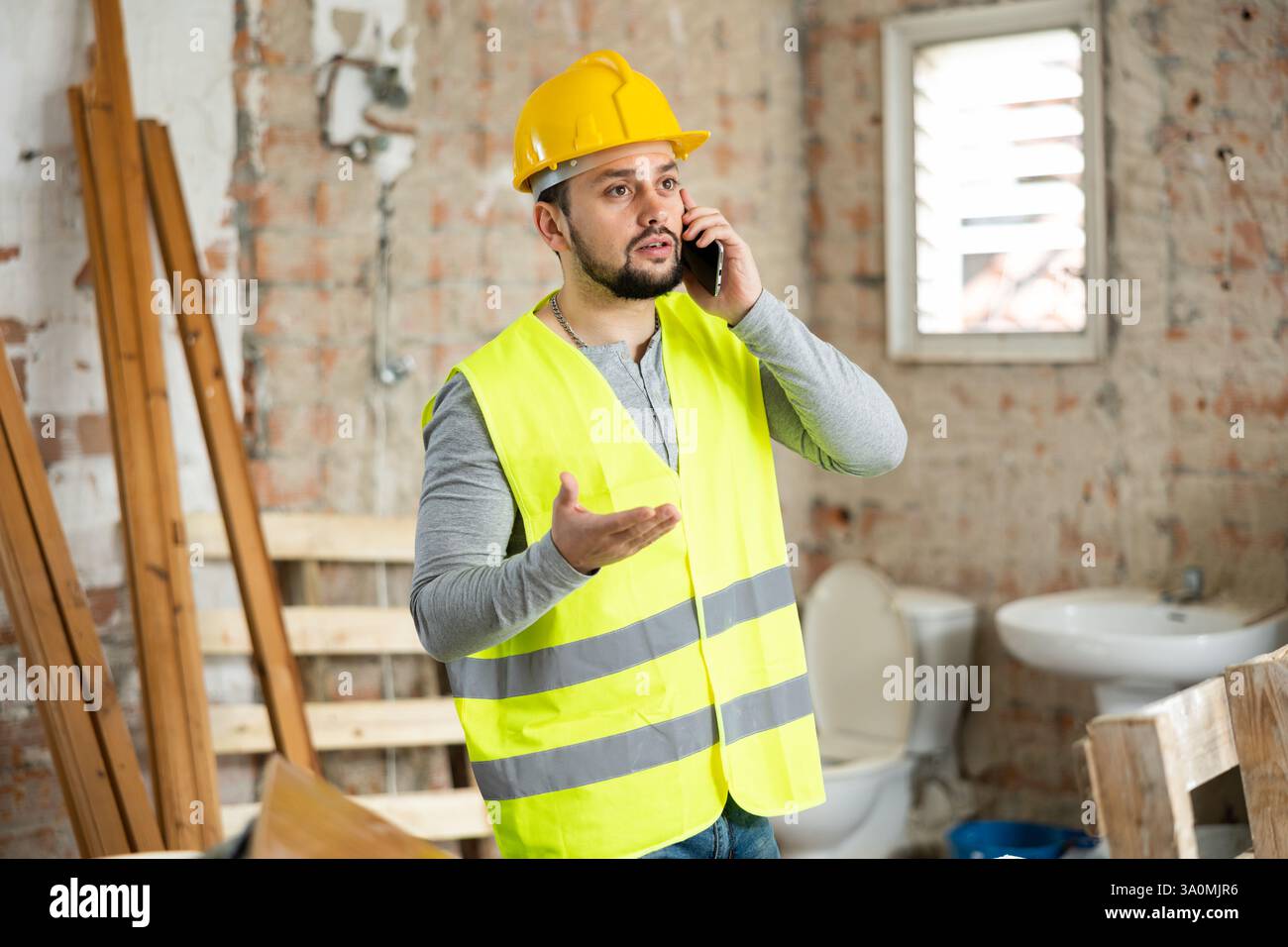 Young bearded civil engineer talking on phone at construction site Stock Photo