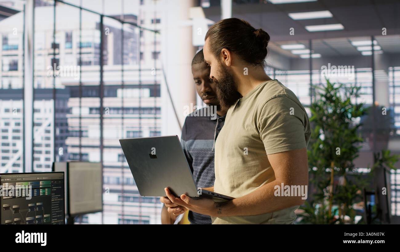 Programmer and colleague conducting experiments and tests to optimize machine learning models for performance and accuracy. IT staff members in office analyzing and interpreting complex data, camera A Stock Photo