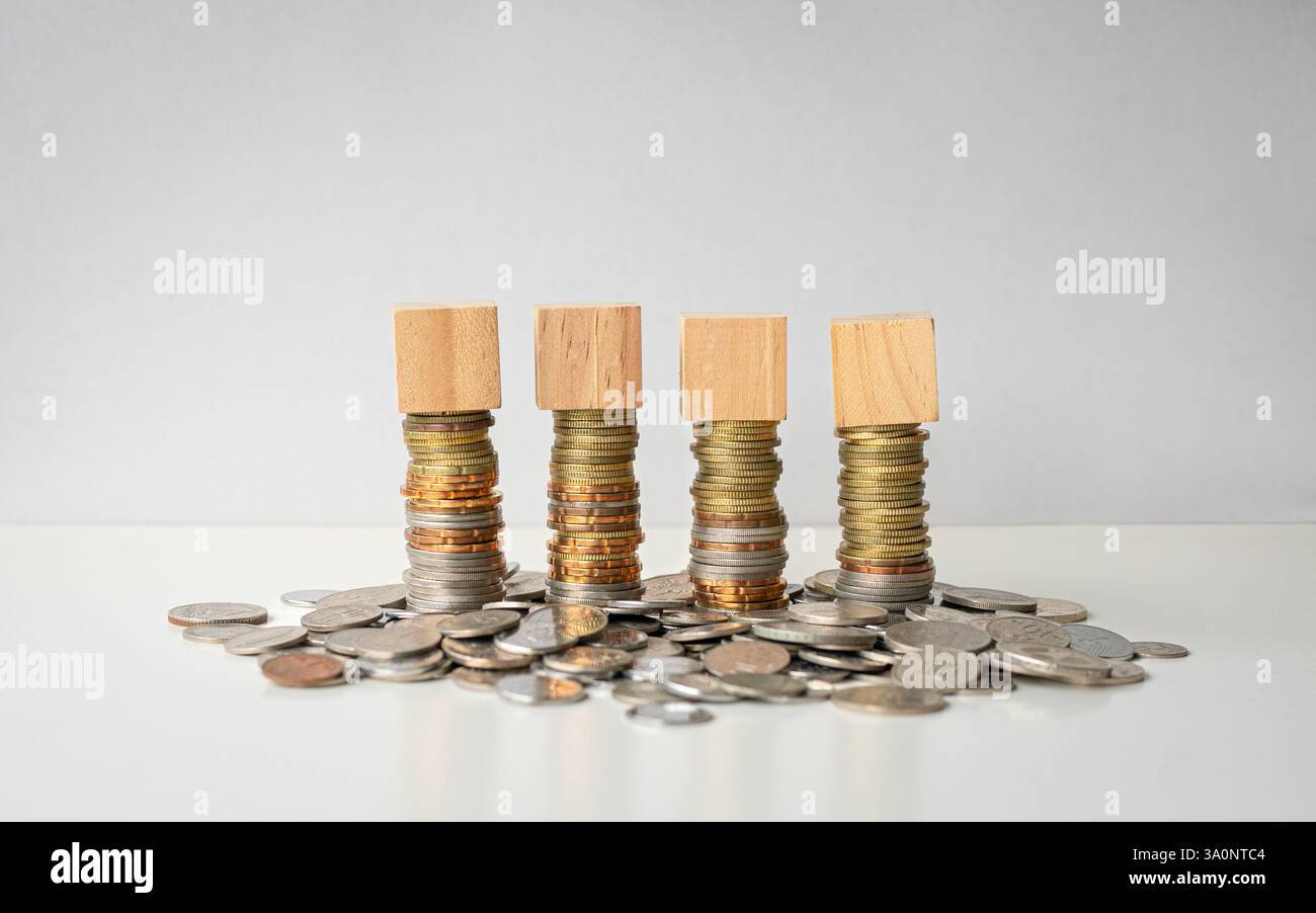 Four blank square wooden blocks on top of stacked coins. Isolated on ...