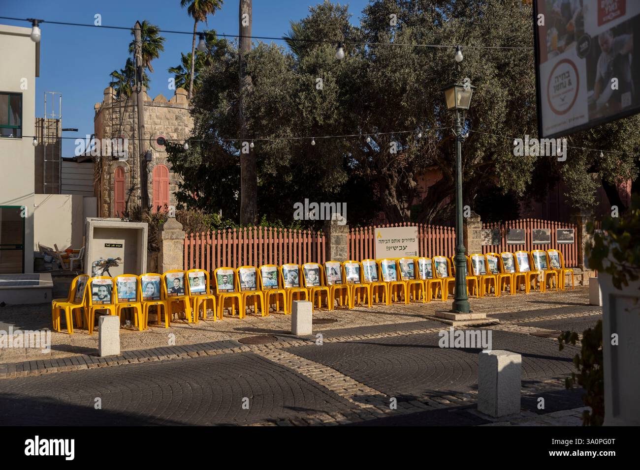 Zikhron Ya'akov, Israel - October 20, 2024, yellow chairs with photographs of Israeli hostages taken by Hamas terrorists on October 7 next to the hous Stock Photo