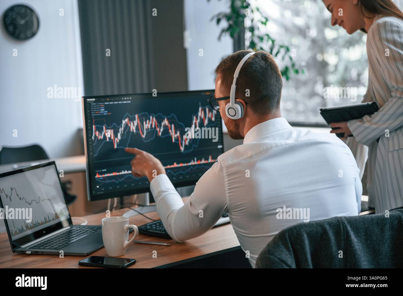 Two office workers are analyzing graphs that on the computer screen. Stock Photo