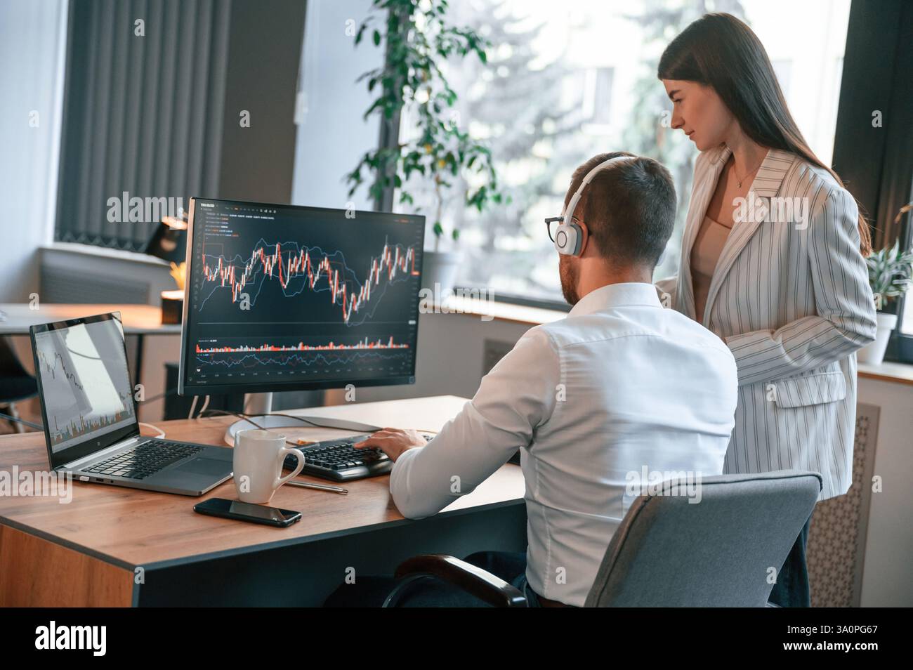 Two office workers are analyzing graphs that on the computer screen. Stock Photo