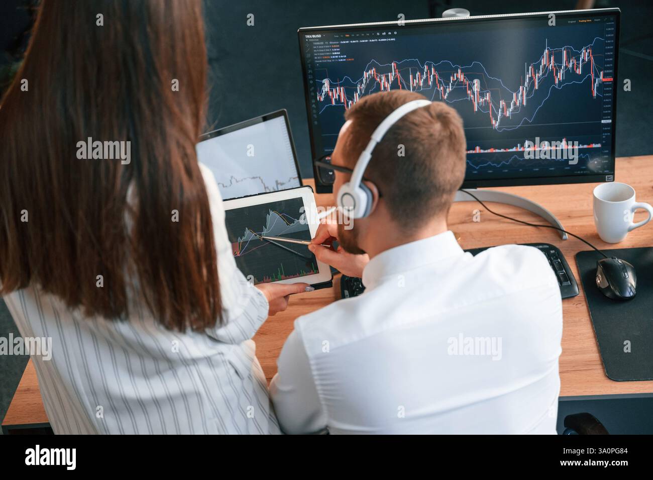 Two office workers are analyzing graphs that on the computer screen. Stock Photo