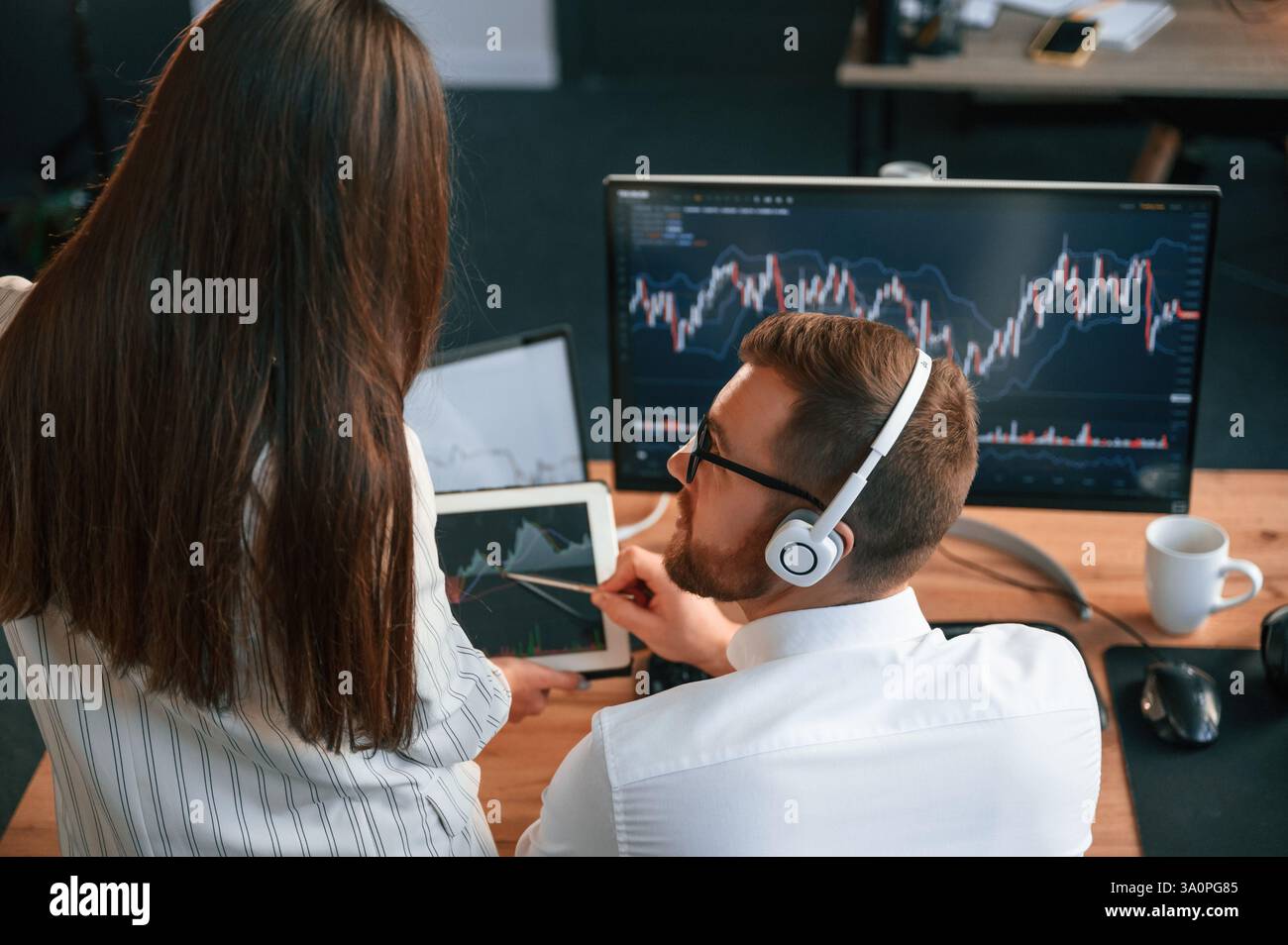 Two office workers are analyzing graphs that on the computer screen. Stock Photo