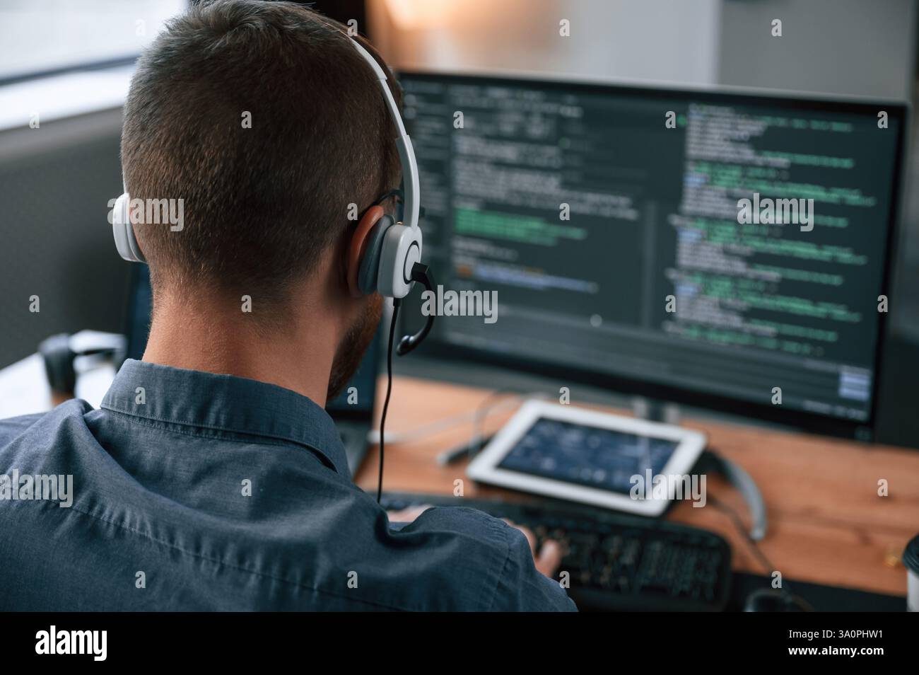 Software developer is writing code. Man in formal clothes is working in the modern office. Using computer. Stock Photo