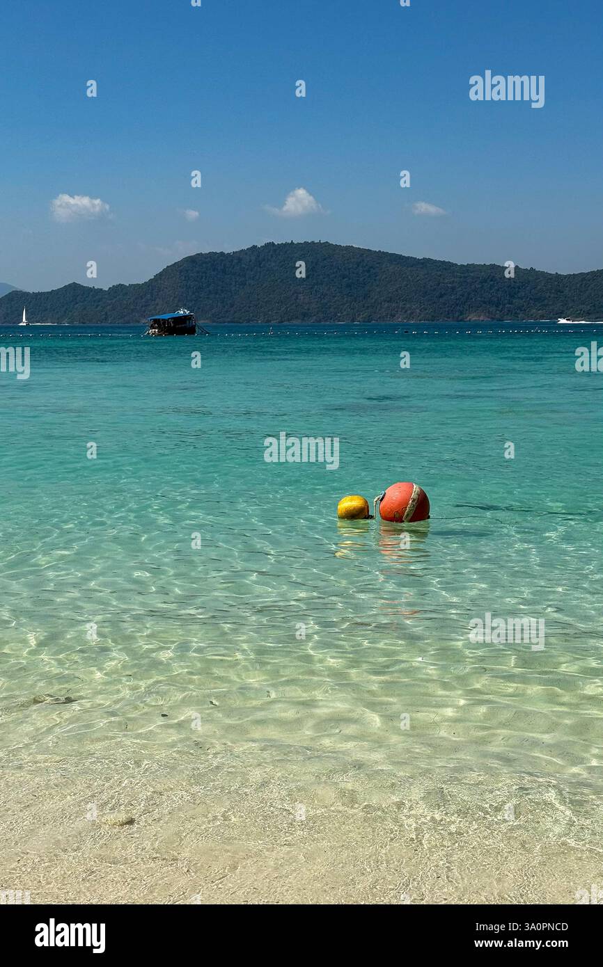 Floating Buoys in Crystal-Clear Waters 3 Two colorful buoys, one red and one yellow, float gently on the stunning turquoise sea. In the background, a - Smartphone Captured Stock Image