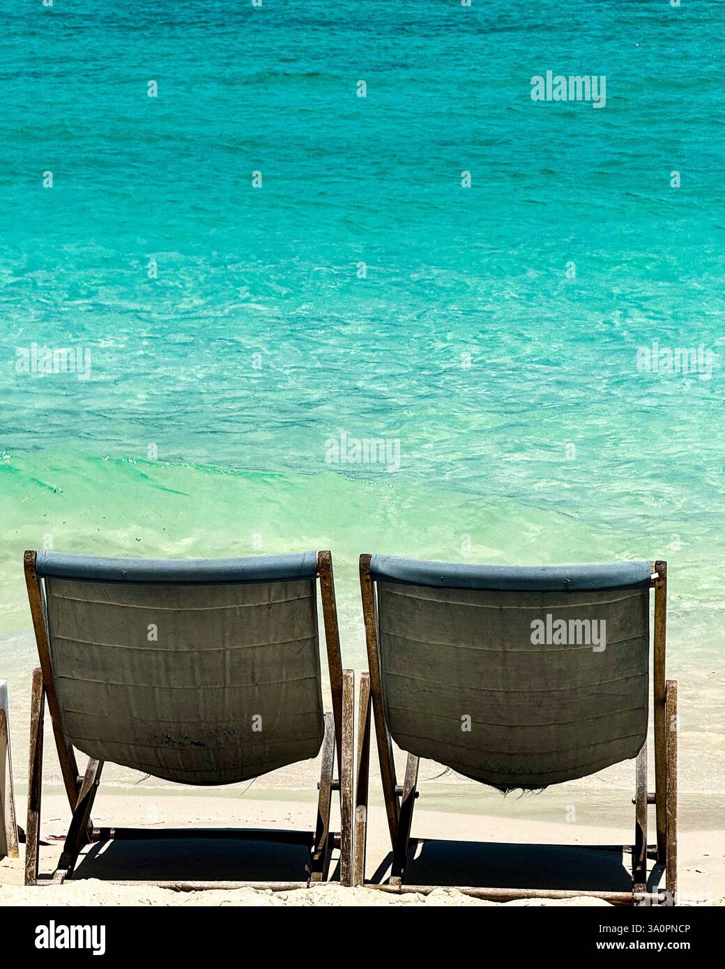 Turquoise Waters and Lounge Chairs in a Tropical Paradise 2 Two wooden lounge chairs sit on a pristine sandy beach, offering a breathtaking view of th - Smartphone Captured Stock Image
