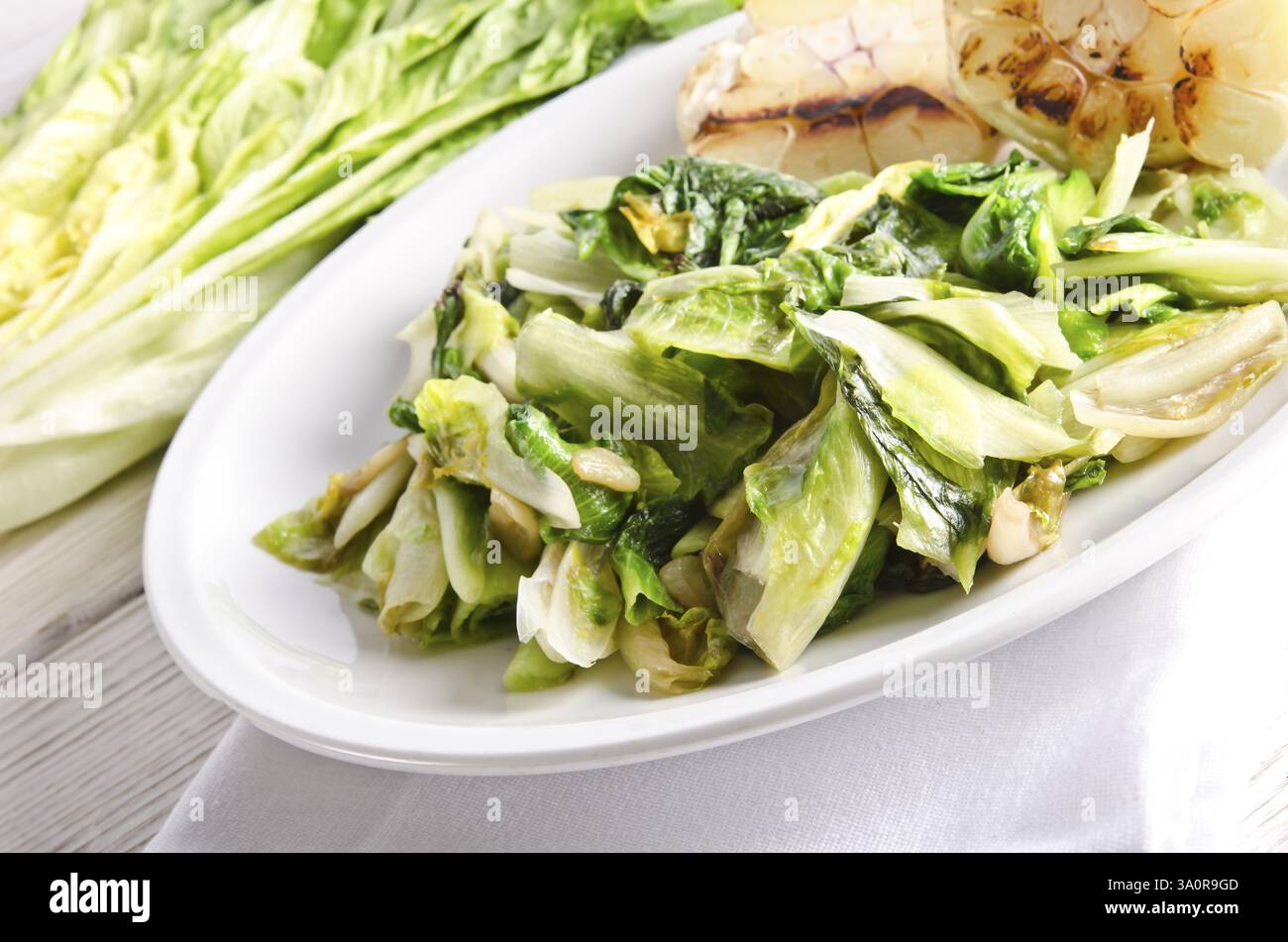 Baked Romaine lettuce with garlic and pine cores Stock Photo - Alamy