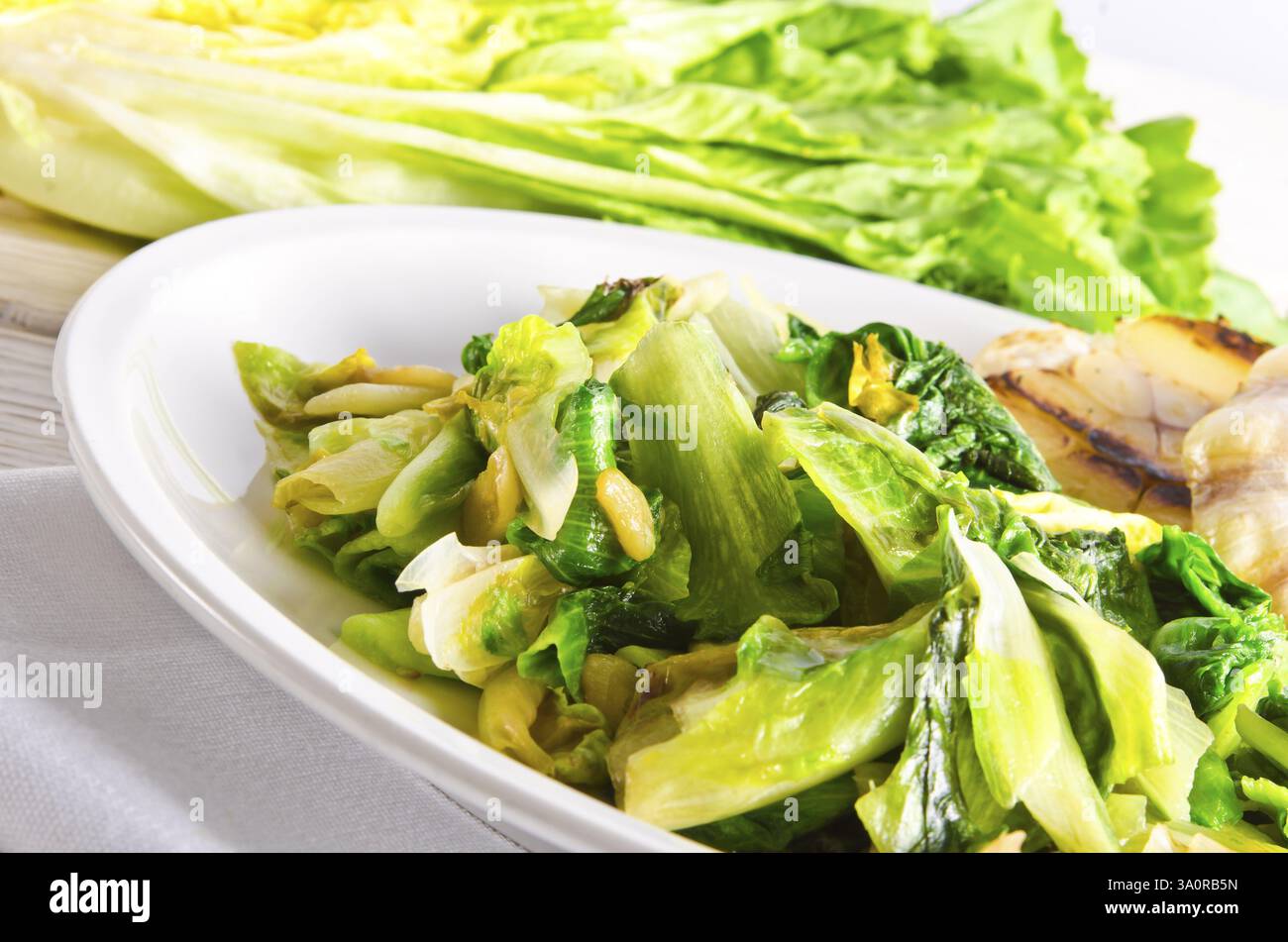 Baked Romaine lettuce with garlic and pine cores Stock Photo - Alamy