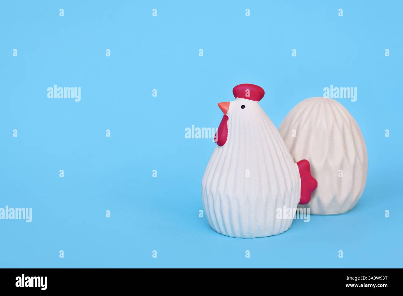 Ceramic Easter chicken and egg decoration objects on blue background with copy space Stock Photo