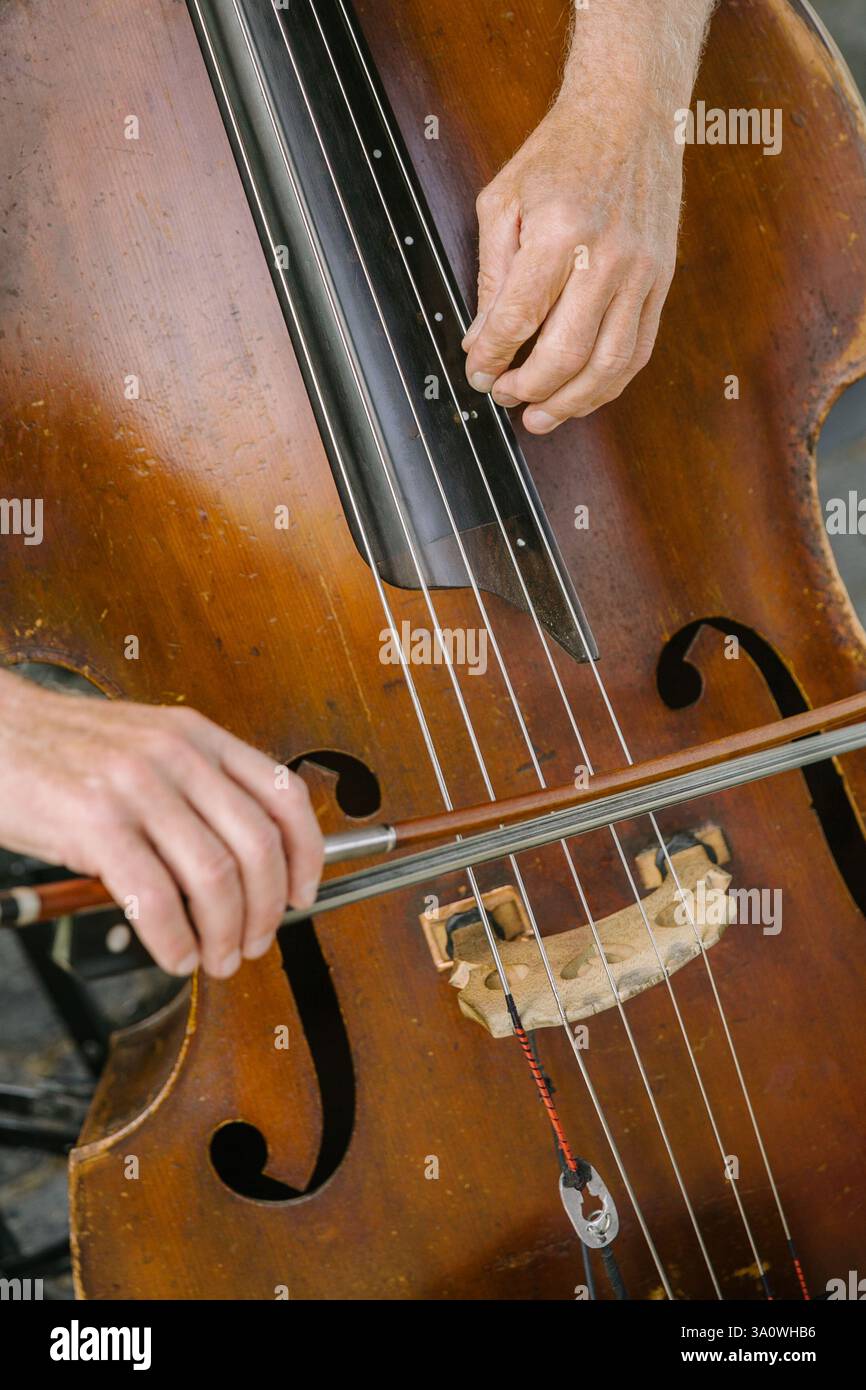 Hands gracefully move on the cello strings, creating beautiful melodies in a lively atmosphere at a music event. Stock Photo