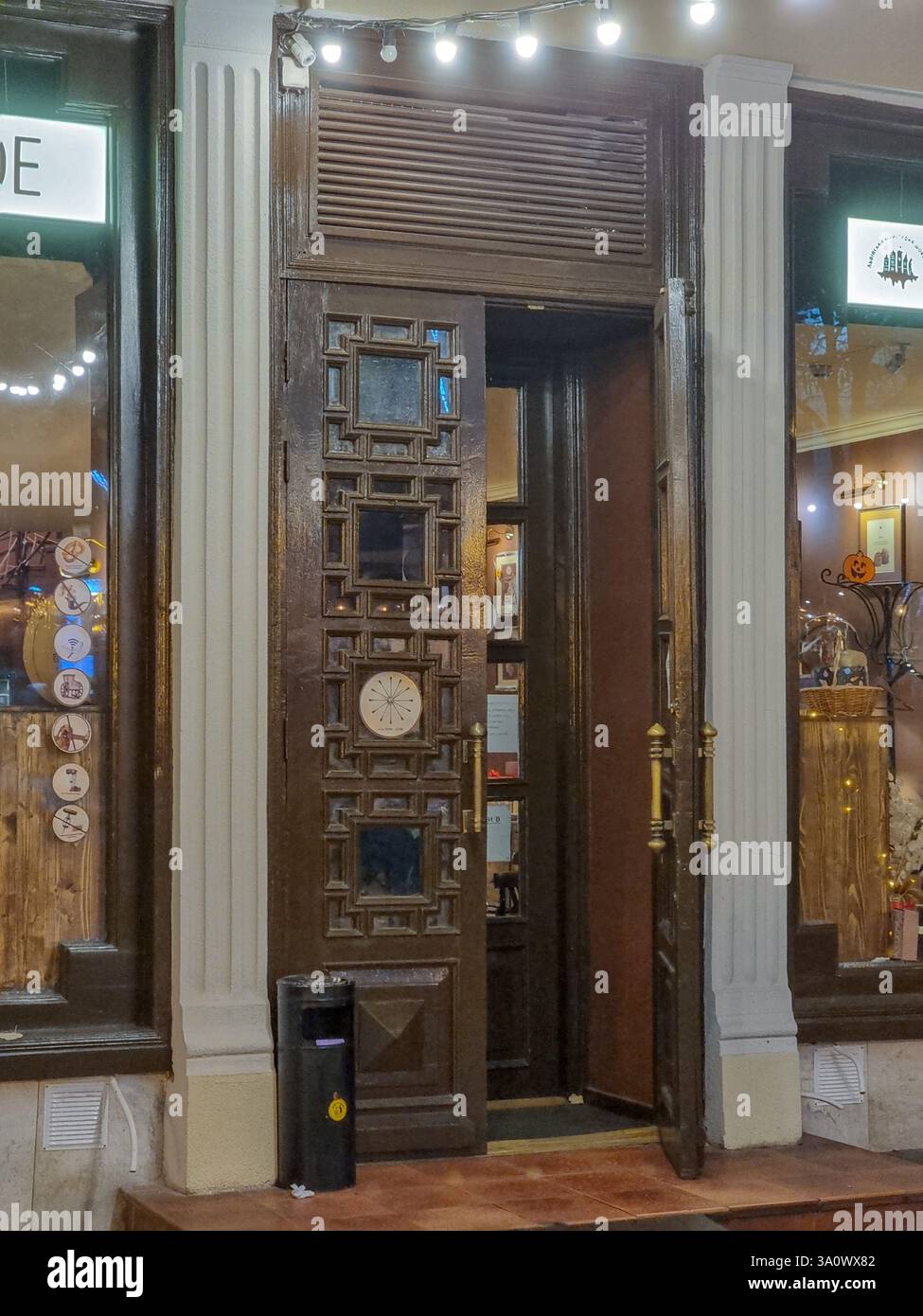 Open wooden door, ornate decorated door, opened door; entrance door with copper handles; waste bin - Smartphone Captured Stock Image