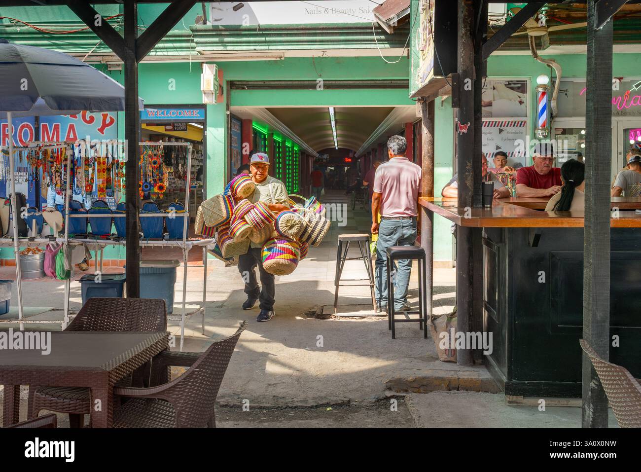Vendor  carries colorful baskets for sale through a tourist area of Nuevo Progreso, Mexico. Stock Photo