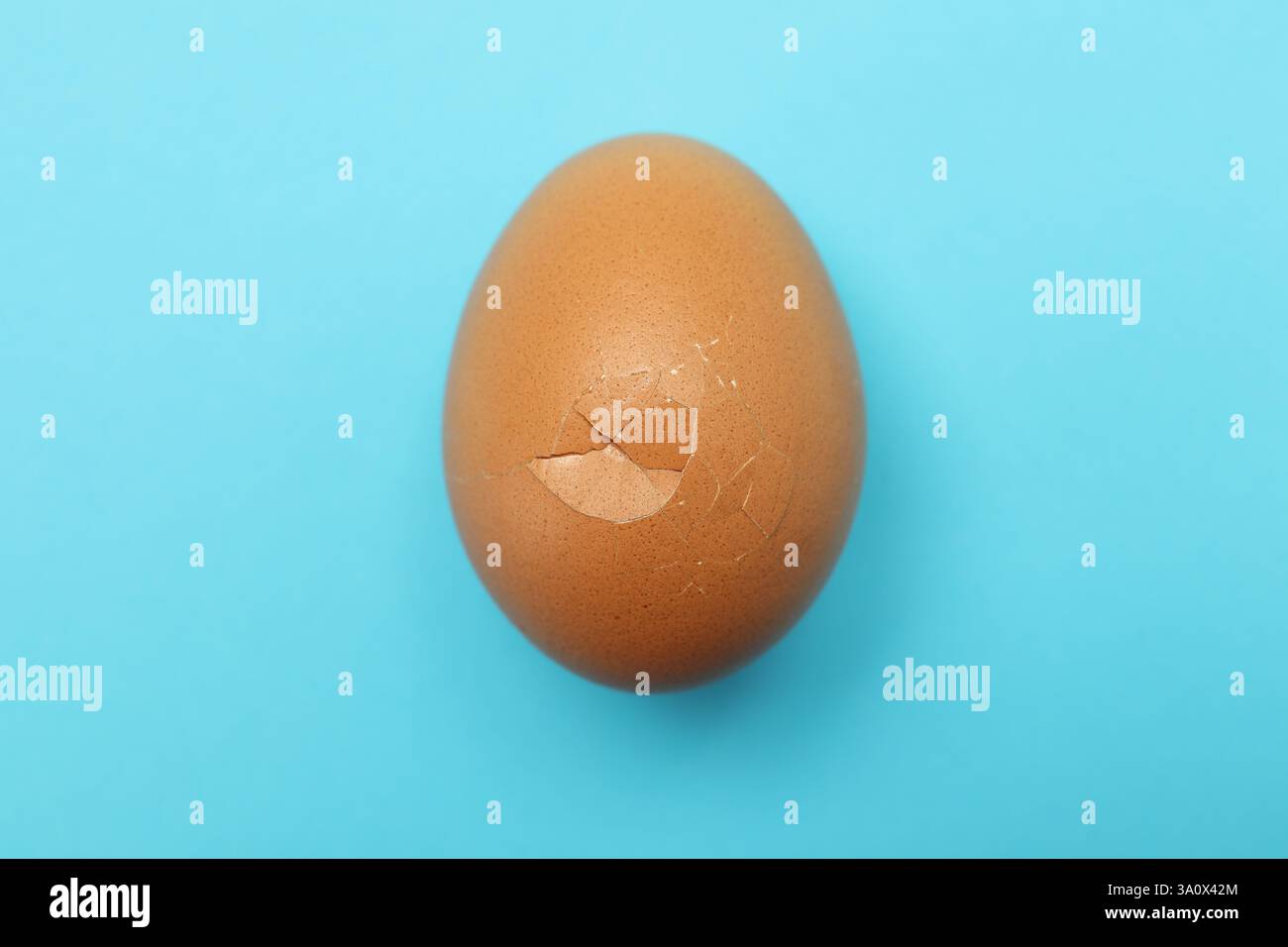 One egg with cracked shell on light blue background, top view Stock Photo