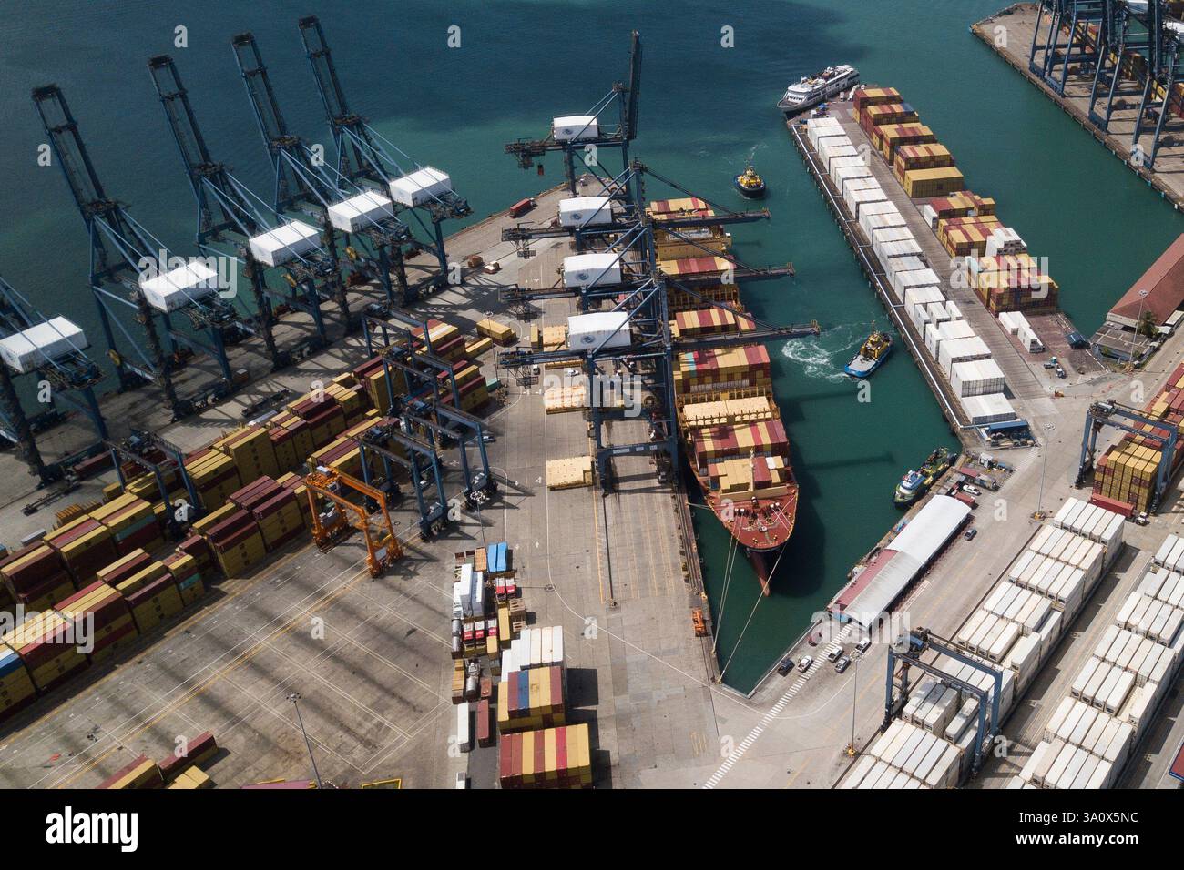 FILE - Cranes load and unload containers from cargo ships at the ...