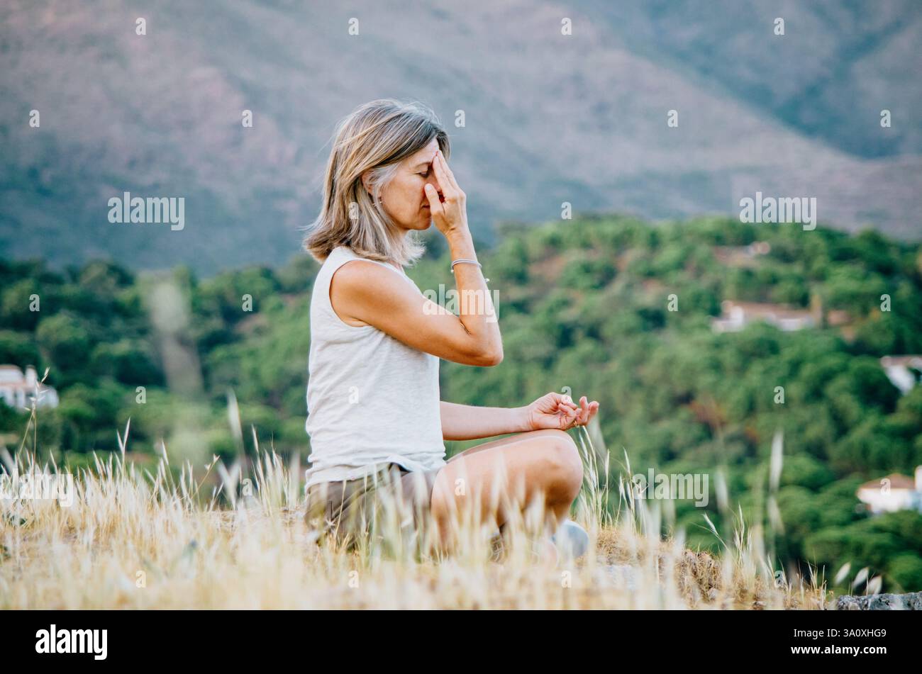 Woman practicing breathing exercises with a mountain landscape background Stock Photo