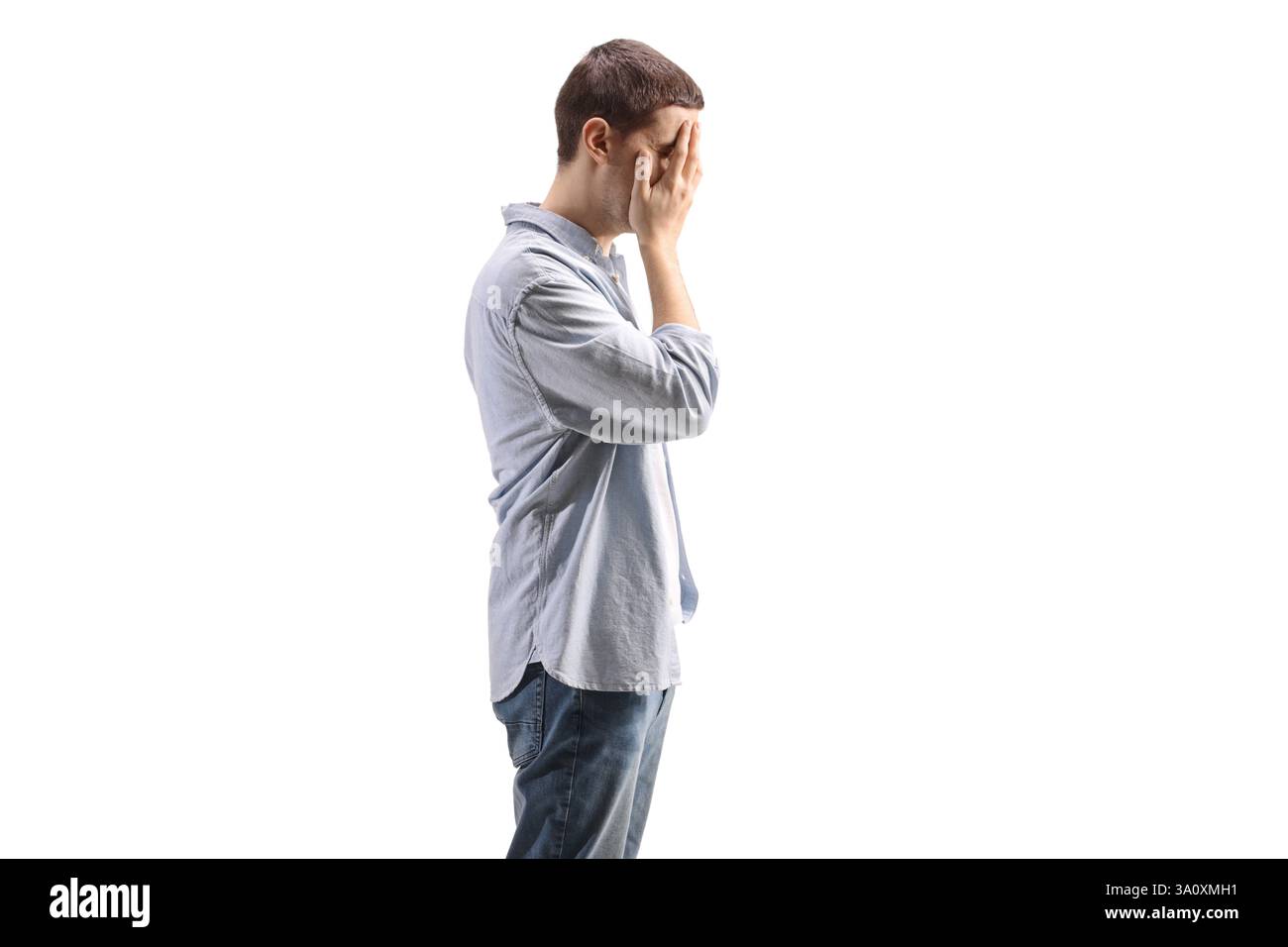 Sad young man covering his face with hands isolated on white background ...
