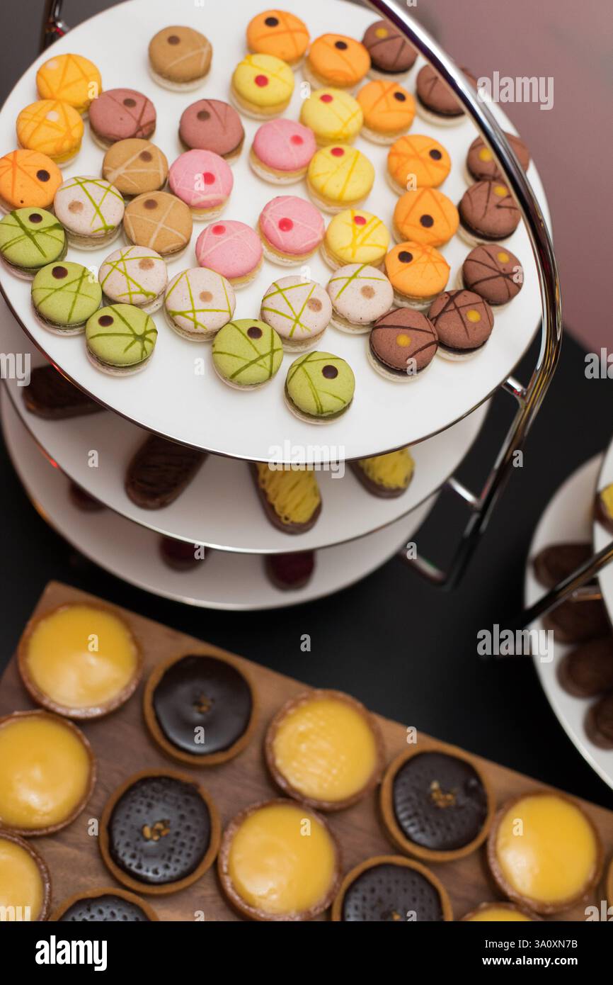 Assorted macarons and tarts displayed on tiered stands Stock Photo