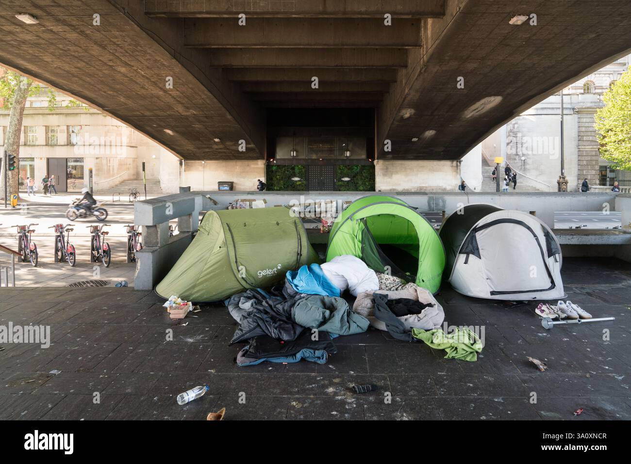 Homeless encampment under Waterloo Bridge, London.  Tents and sleeping bags are visible.  A social issue. Stock Photo