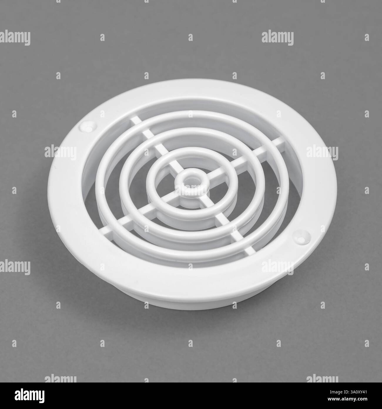 White ventilation grate on a gray background. Round shape. An element of the ventilation system. Stock Photo