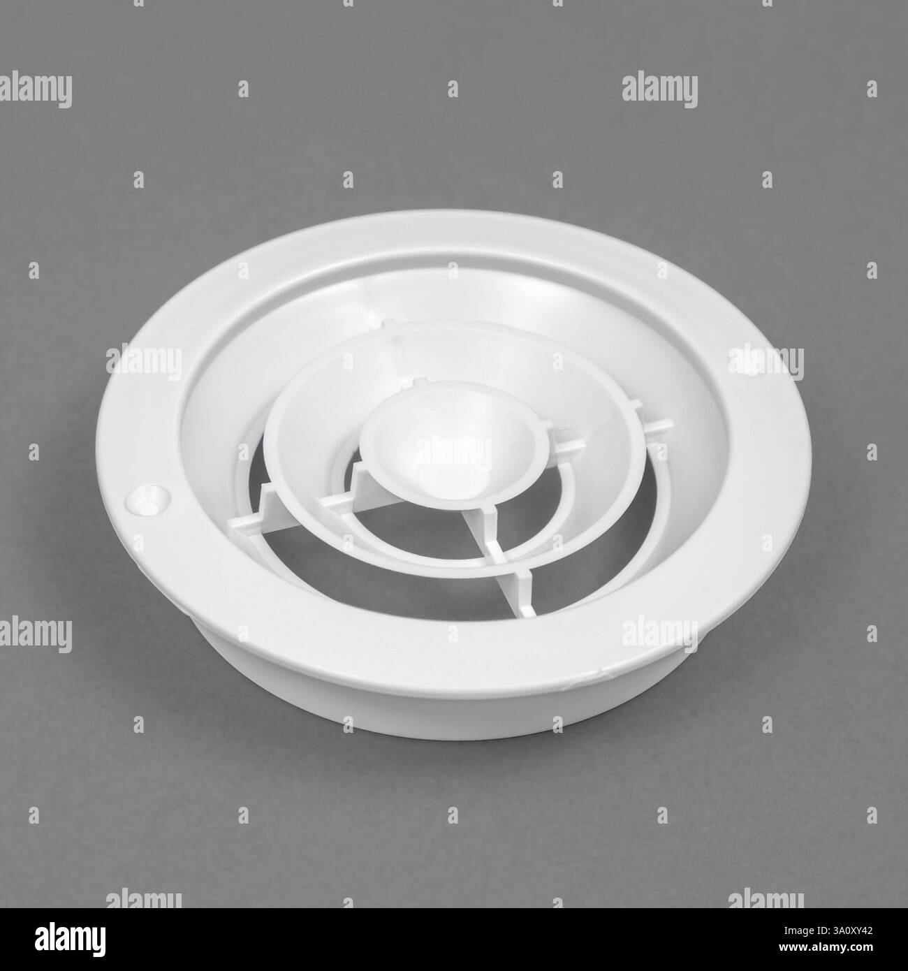 White ventilation grate on a gray background. Round shape. An element of the ventilation system. Stock Photo