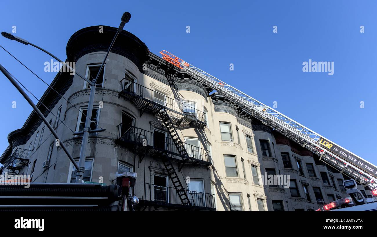 FDNY fire trucks responding to an apartment fire on Bedford Avenue in Brooklyn New York City with ladders into broken windows. Stock Photo