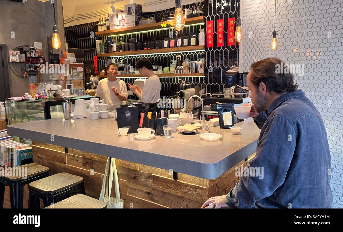 A customer enjoying a cup of coffee at the Flow coffee shop in Sham Shui Po, Kowloon, Hong Kong. - Smartphone Captured Stock Image