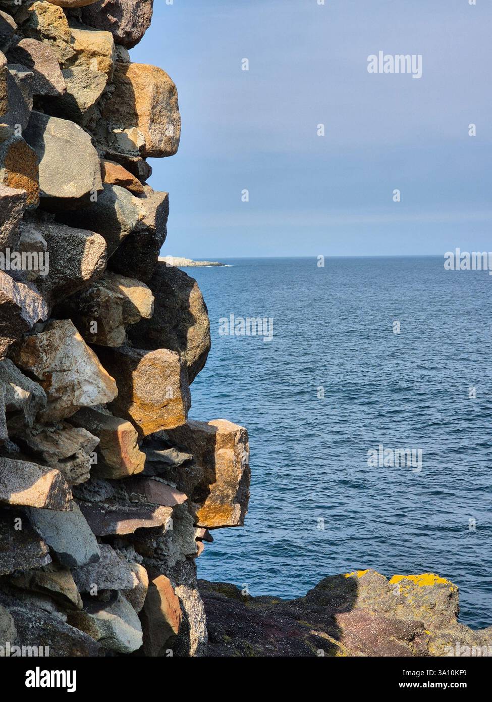 Where the rocks meet the sea. unusual stone wall near the sea - Smartphone Captured Stock Image
