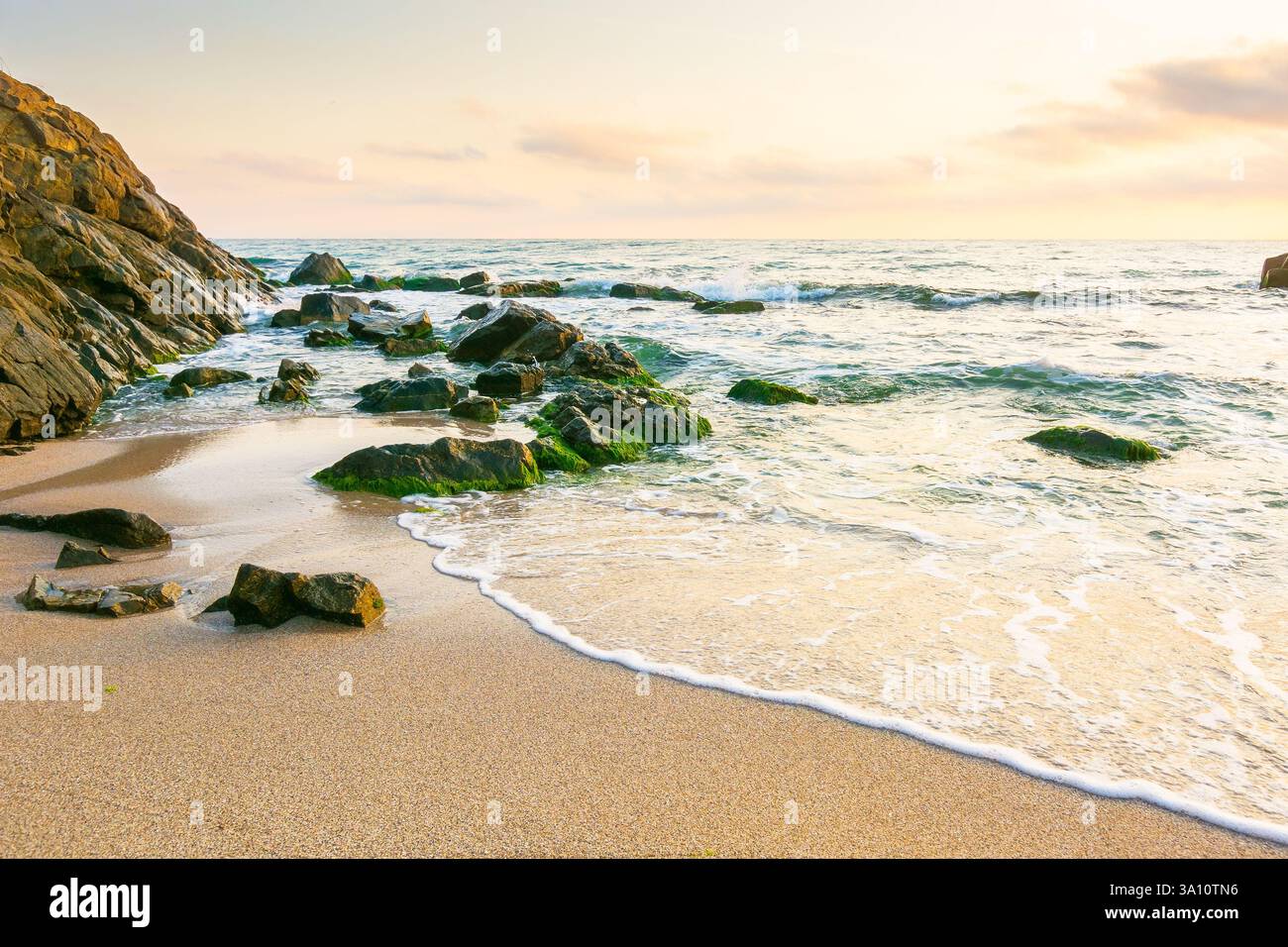 summer holiday season at the seaside. beautiful seascape at sunrise. golden sandy beach in morning light. sun behind fluffy clouds on sky above horizo Stock Photo