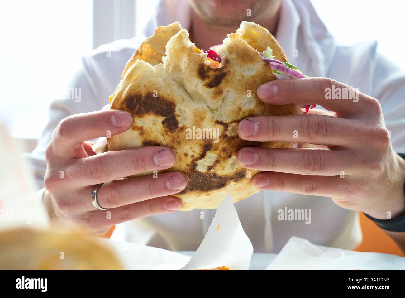 Karlsruhe, Baden-Württemberg, Germany - March 4, 2025: A young man eats ...