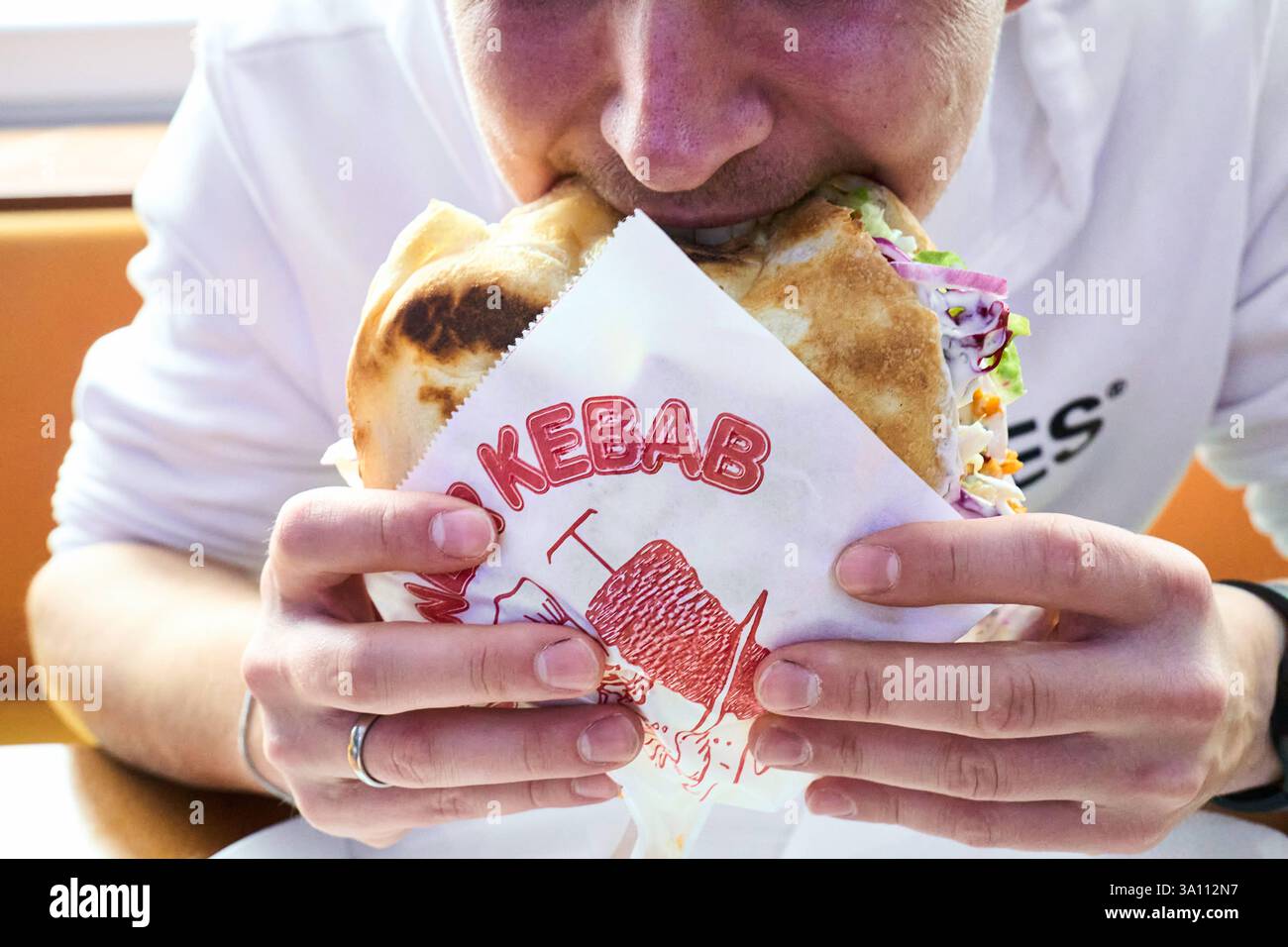 Karlsruhe, Baden-Württemberg, Germany - March 4, 2025: A young man eats ...