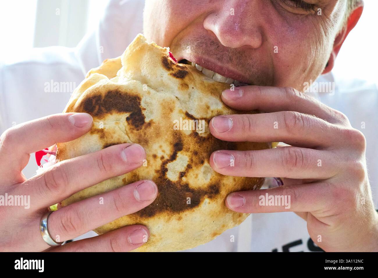 Karlsruhe, Baden-Württemberg, Germany - March 4, 2025: A young man eats ...
