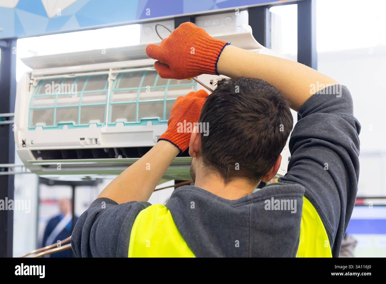 A worker installing an indoor air conditioner unit. Industry Stock Photo