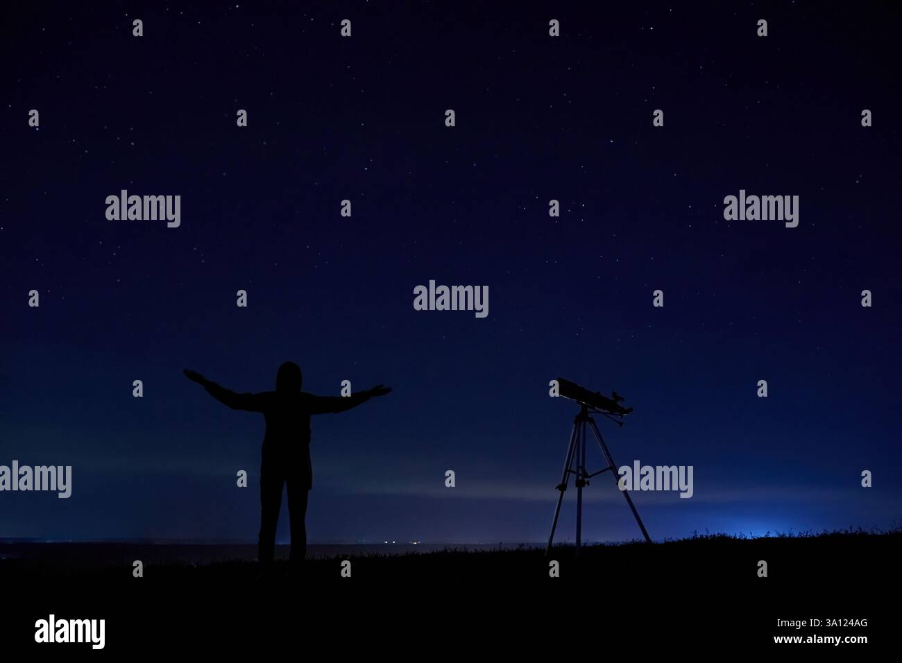 Silhouette of a man near an optical telescope outdoors at night with a ...