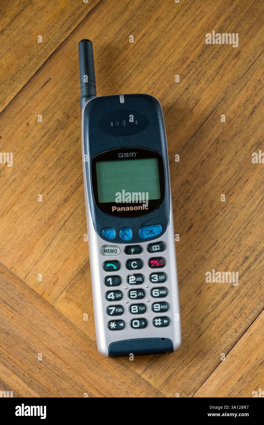 Old Panasonic G500 cellular phone resting on a wooden surface, representing a nostalgic view of communication technology Stock Photo