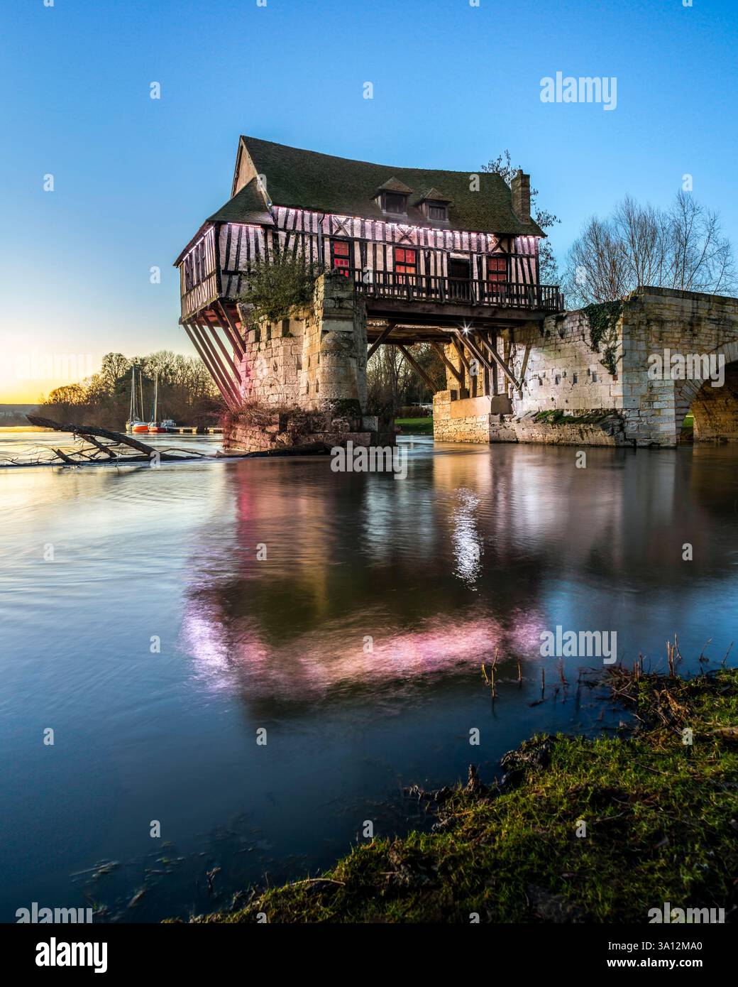 France, Eure, Vernon, reflection of the Old Mill on the water of the Seine river, illuminated at sunset Stock Photo