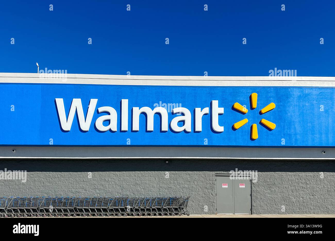 Walmart store sign and shopping carts against blue sky. Merrillville, IN USA March 6, 2025 - Smartphone Captured Stock Image